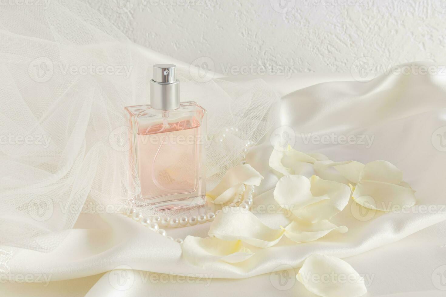 un elegante botella de femenino perfume o eau Delaware perfume en un antecedentes de satín tela con suave color champagne ondas. blanco Rosa pétalos foto