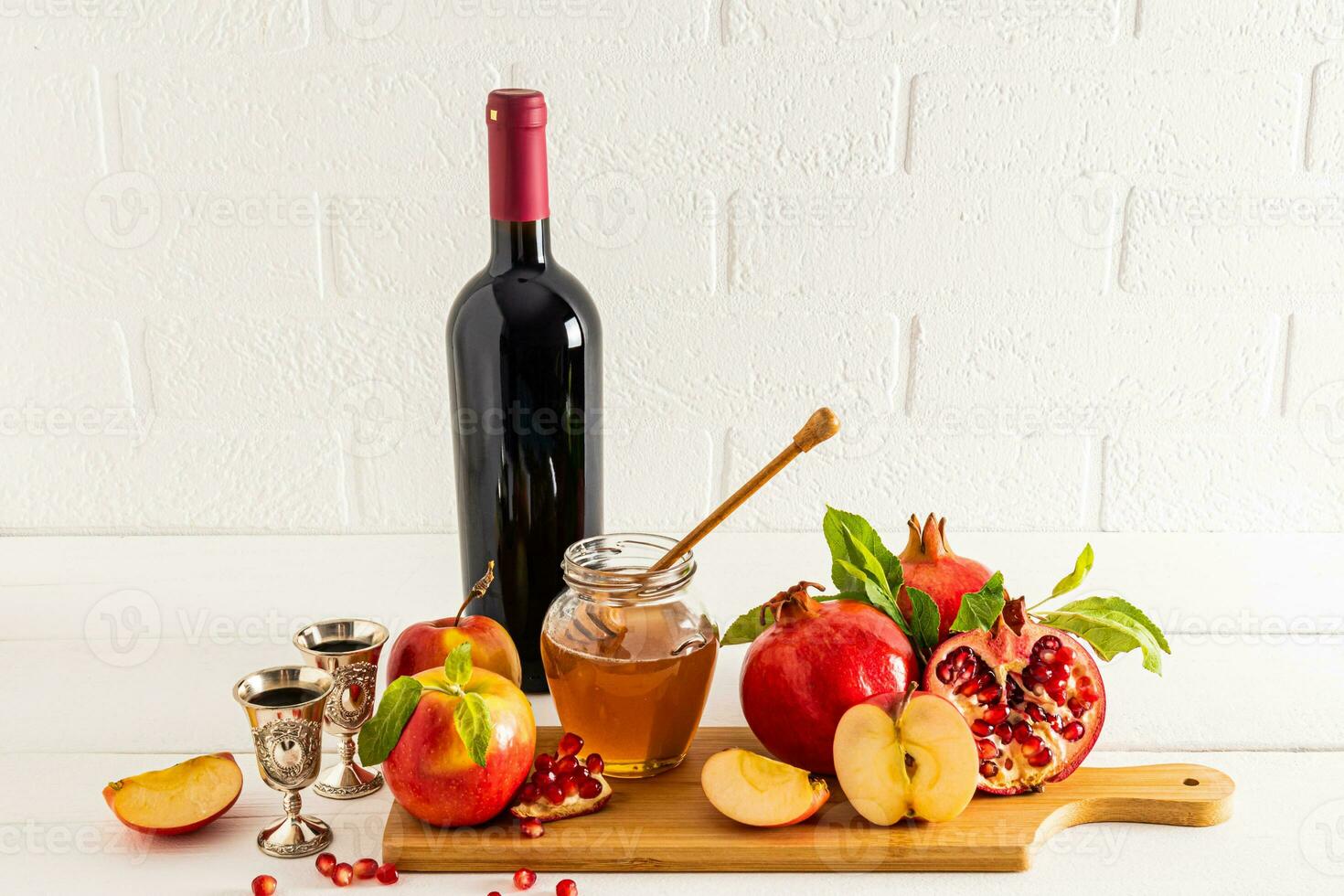 un conjunto de tradicional comida y un botella de rojo vino para rosh hashaná en contra el fondo de un blanco ladrillo pared. frente vista. judío nuevo año. foto