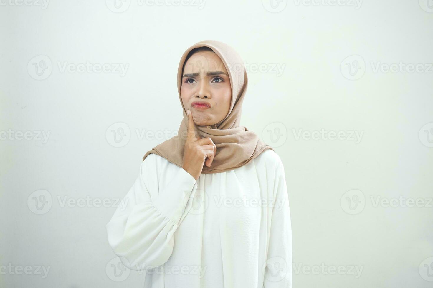 Portrait of thinking young Asian woman looking up and touch chin isolated on over white background photo
