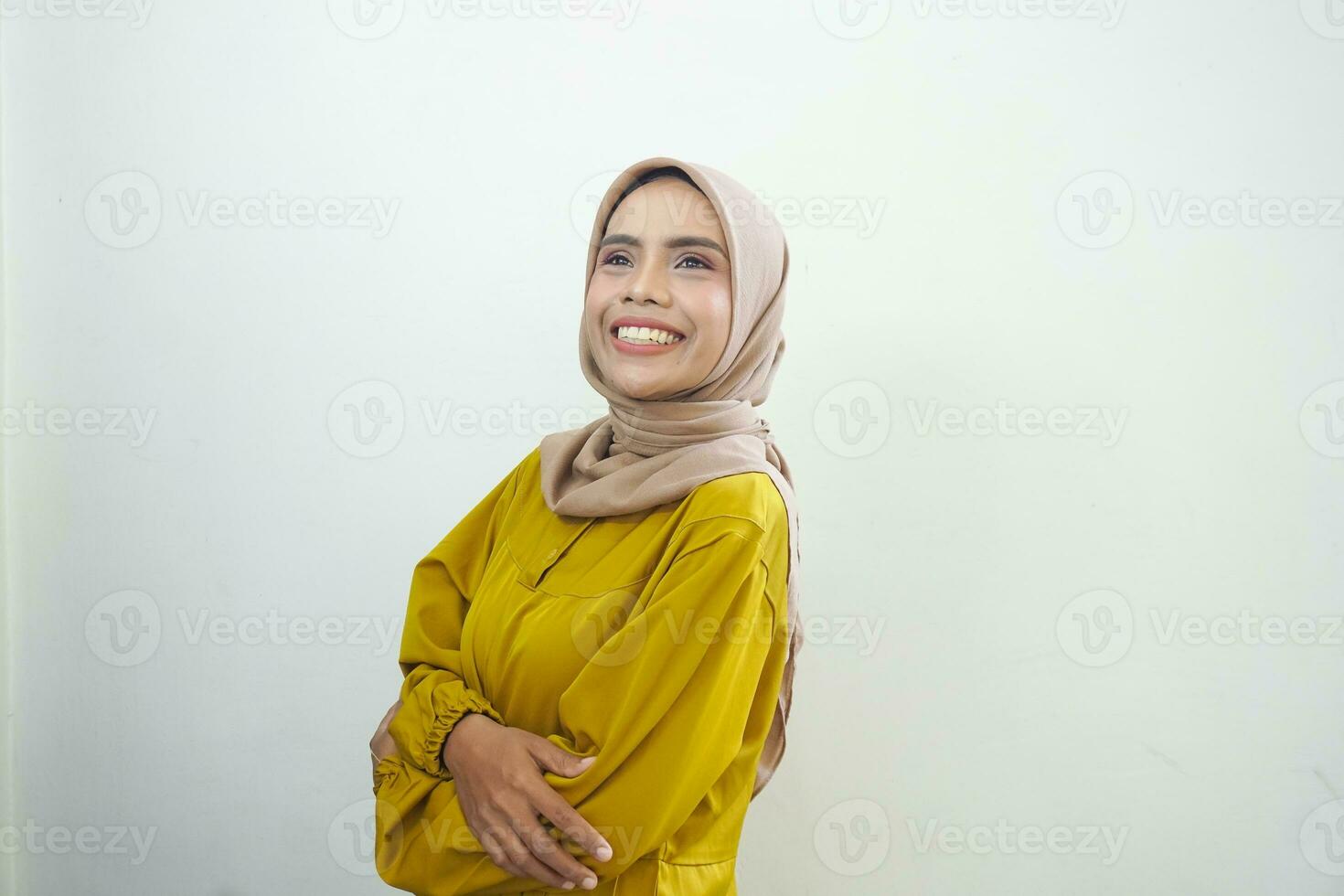 Portrait of a confident smiling Asian Muslim woman wearing hijab standing with arms folded isolated over white background photo