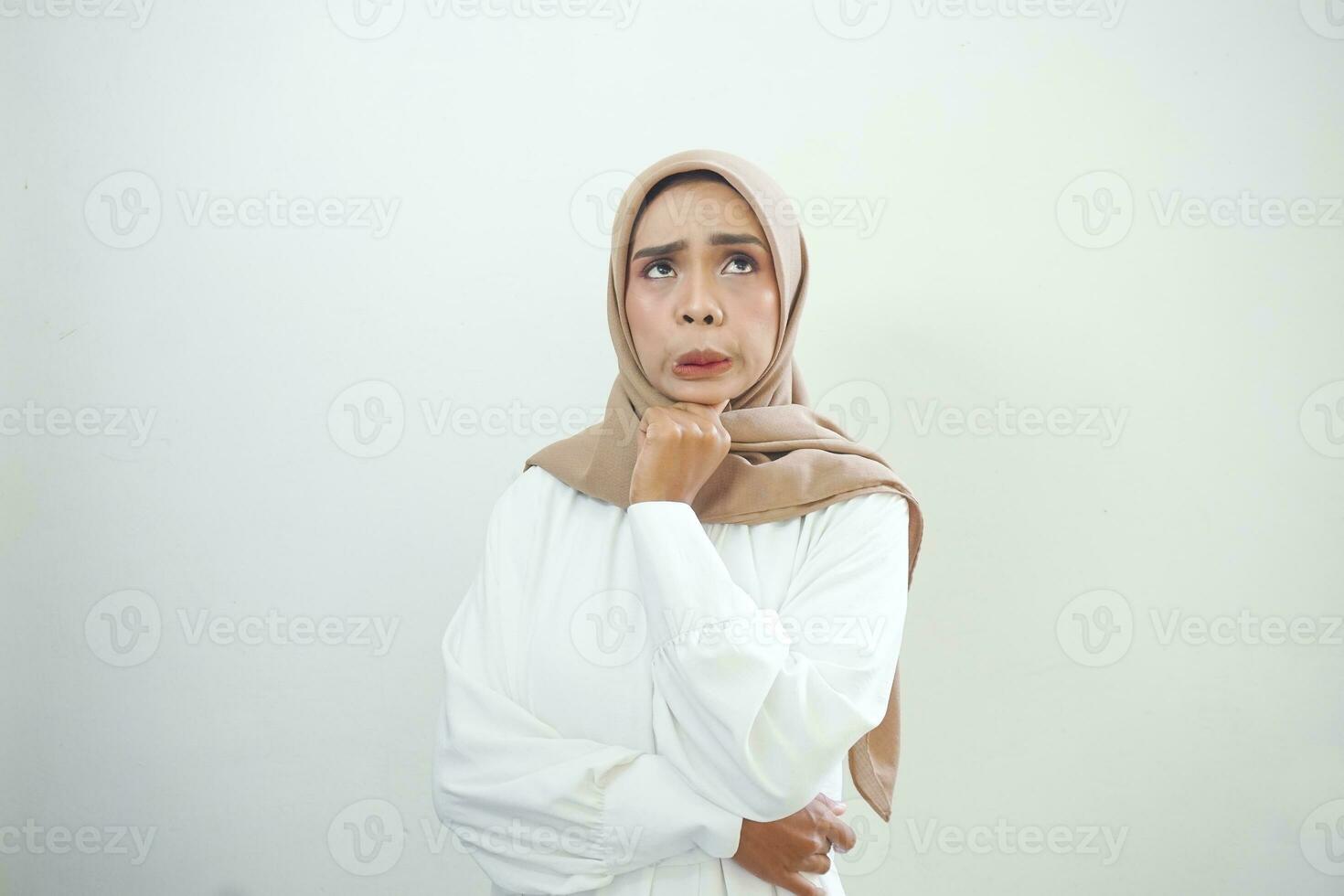 Portrait of thinking young Asian woman looking up and touch chin isolated on over white background photo
