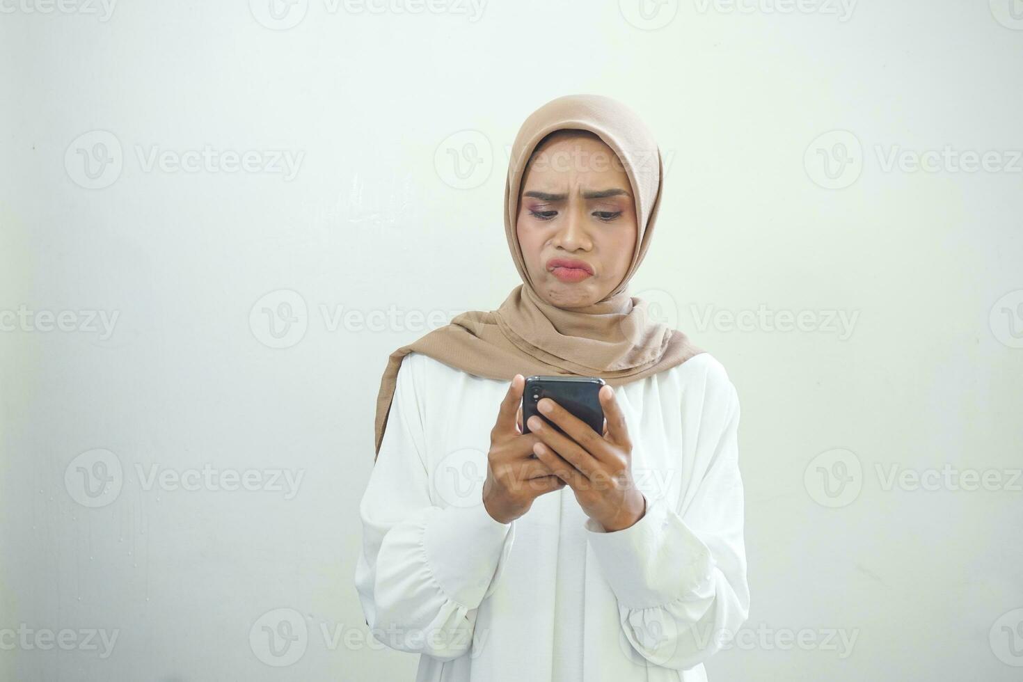 Beautiful smiling Asian Muslim woman wearing hijab Using mobile phone, typing sms message isolated on white background studio portrait. People religious lifestyle concept photo