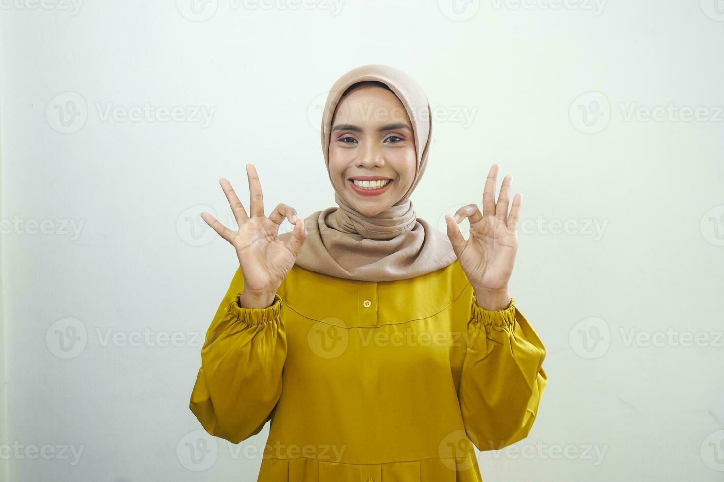 Smiling young Asian woman in white casual showing okay gesture isolated on white background photo