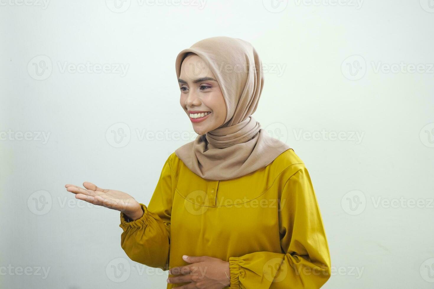 Smiling young Asian Muslim woman gesturing Eid Mubarak greeting isolated over white background photo
