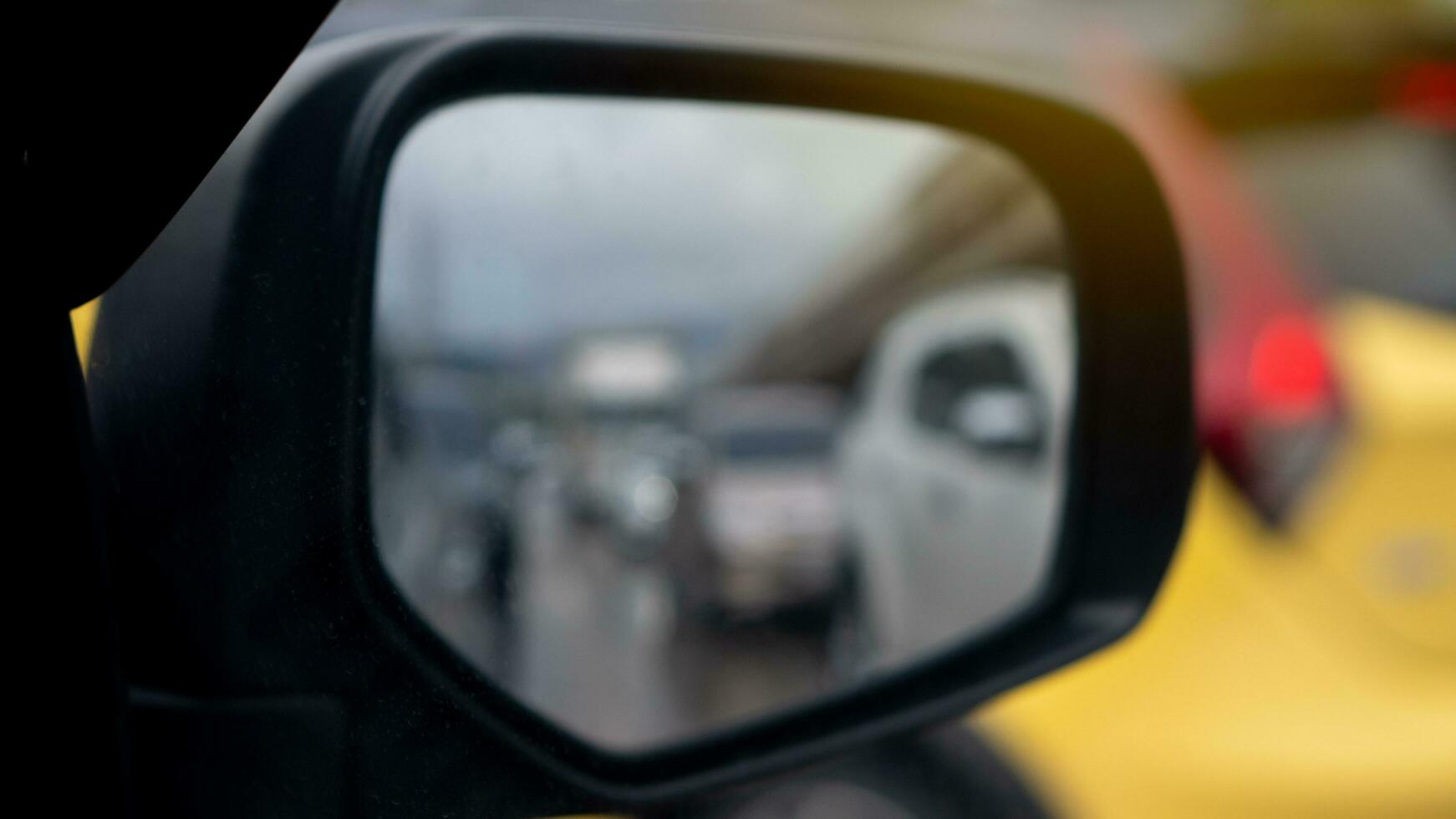 Abstract wing mirror view of car. Looking back for drving in the city can see blurred of yellow car. photo