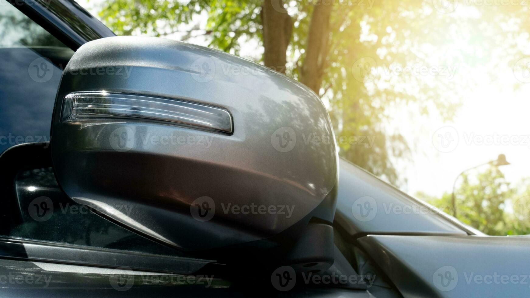 Side view of gray car closeup on teh mirror wing. Folding turn signal with turn signal installation. Blurred background nature trees and sunlight. photo