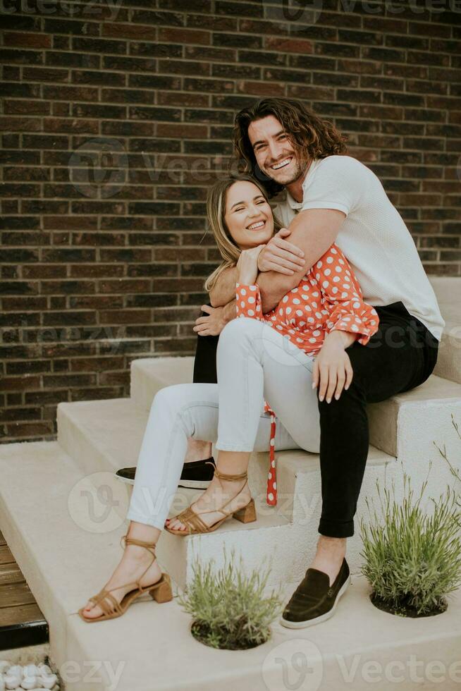 Smiling young couple in love in front of house brick wall photo