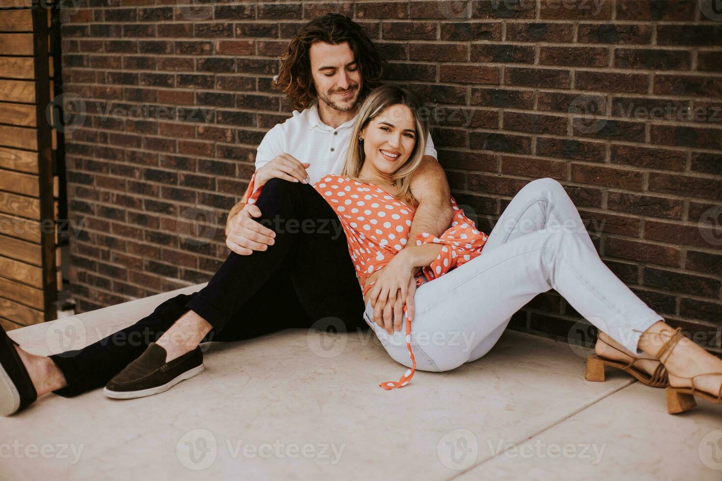 Smiling young couple in love in front of house brick wall photo