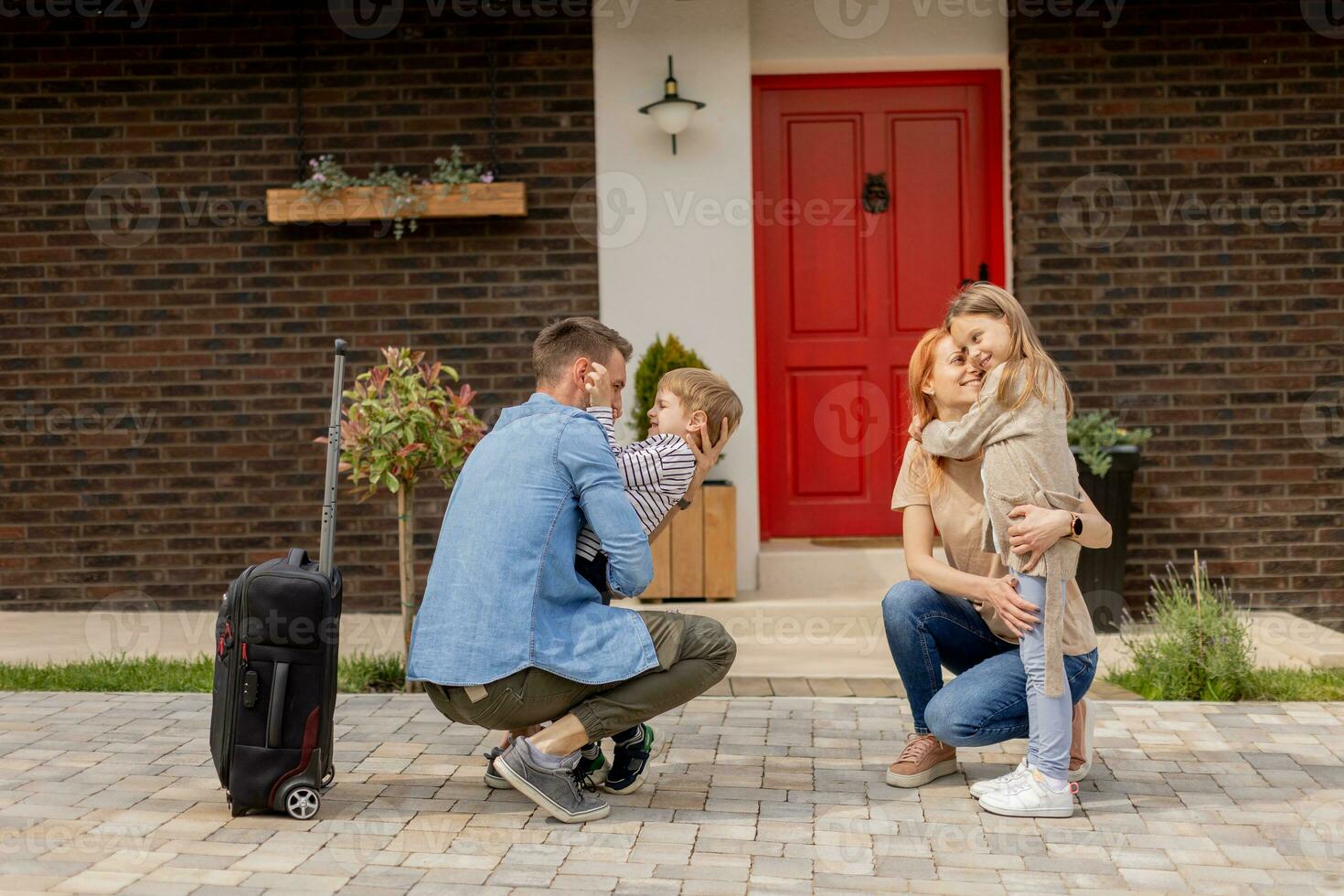 Father came home from the trip and son, daughter and wife greeting him photo