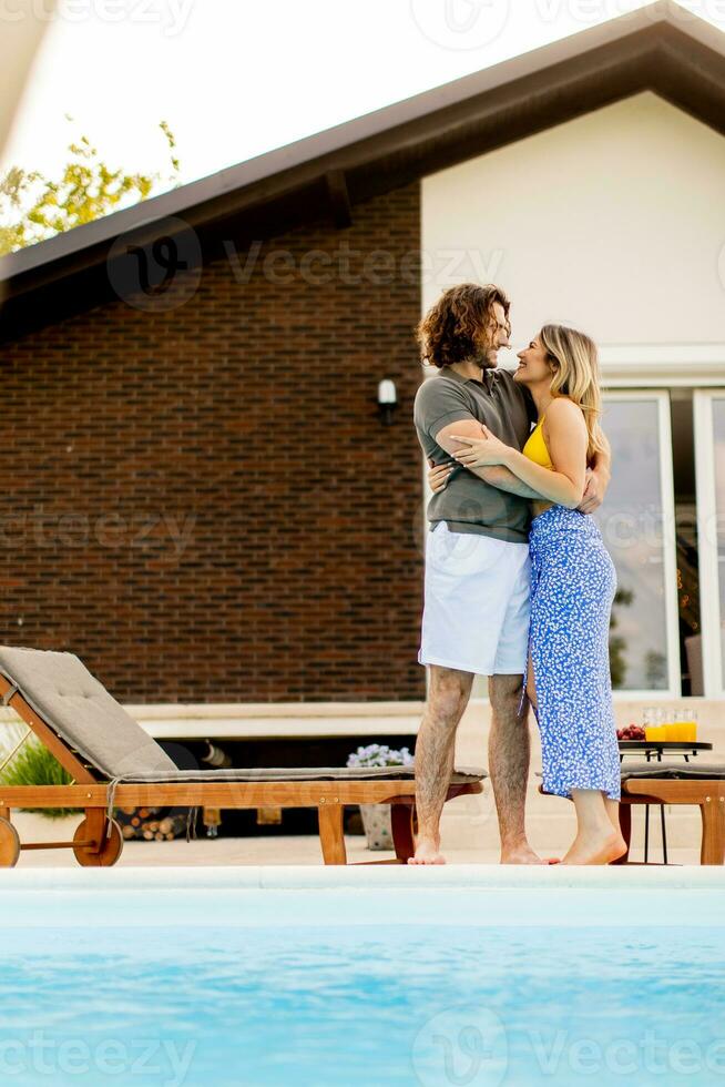 Young couple relaxing by the swimming pool in the house backyard photo