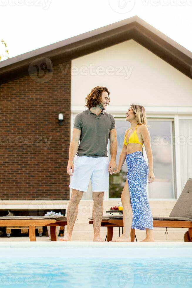 Young couple relaxing by the swimming pool in the house backyard photo