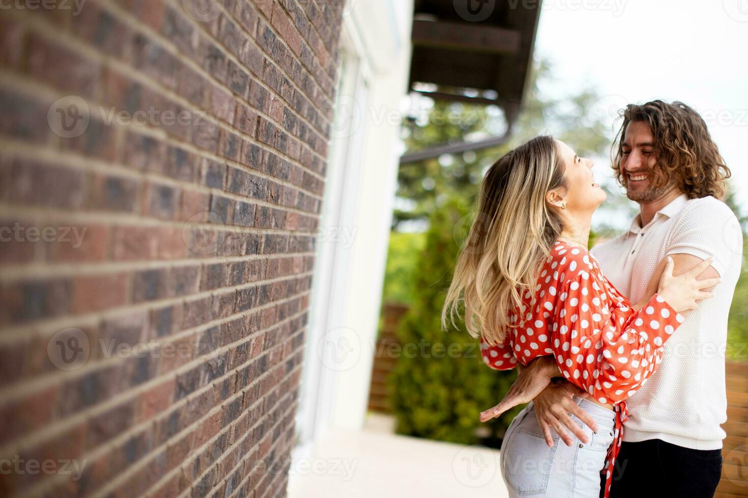 Smiling young couple in love in front of house brick wall photo