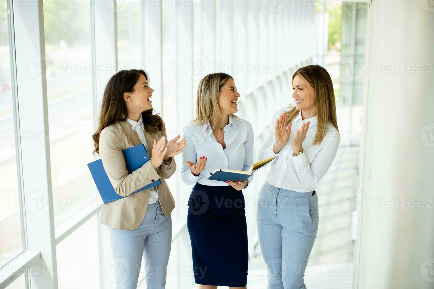 Three young business women walking on stairs in the office hallway photo
