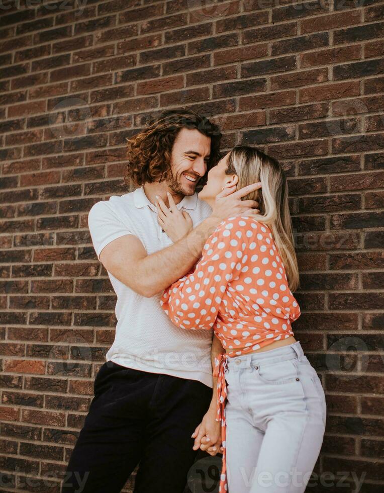 Smiling young couple in love in front of house brick wall photo