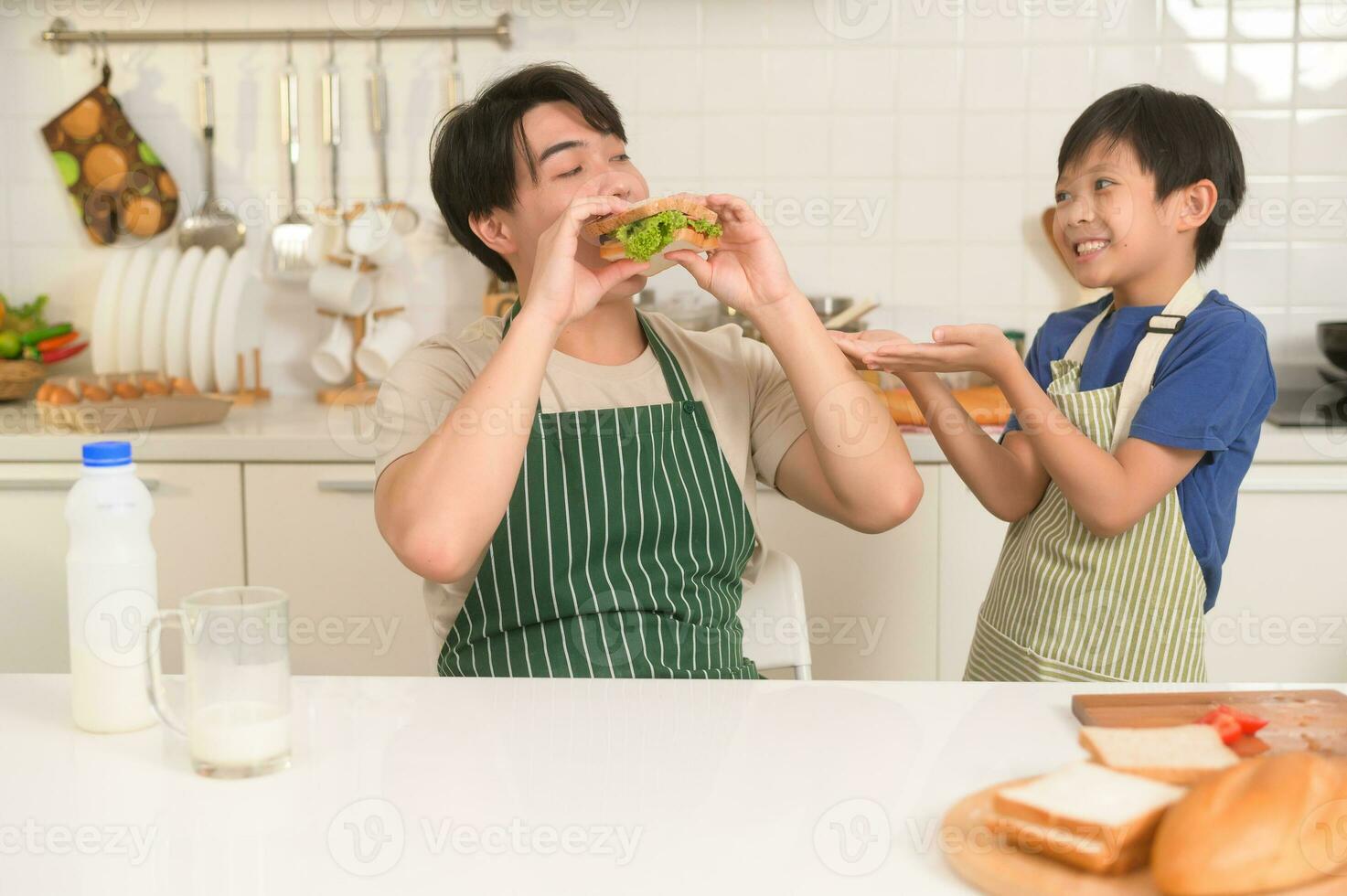 contento joven asiático padre y hijo comiendo sano comida en cocina a hogar foto