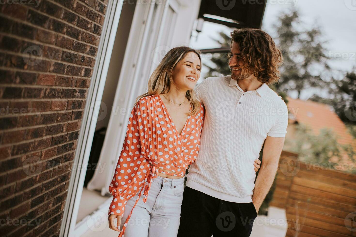 Smiling young couple in love walking  in front of house brick wall photo