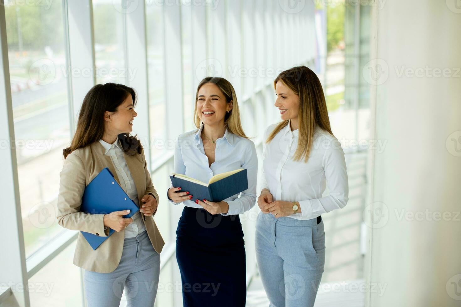 Three young business women having a discussion while walking in the office hallway photo