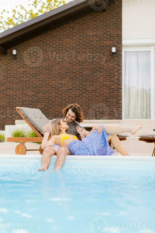 Young couple relaxing by the swimming pool in the house backyard photo