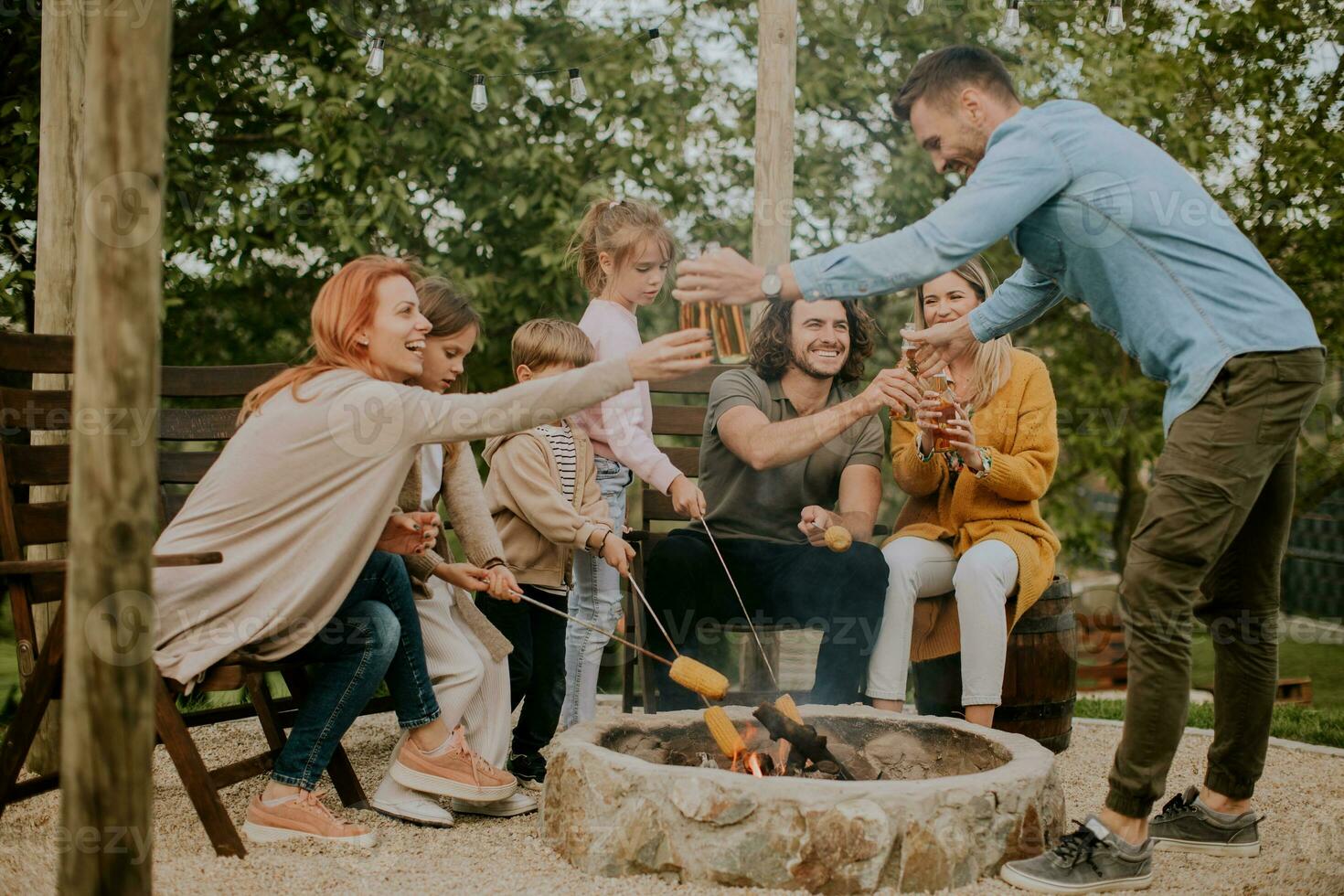 Friends having good time and baking corns in the house backyard photo