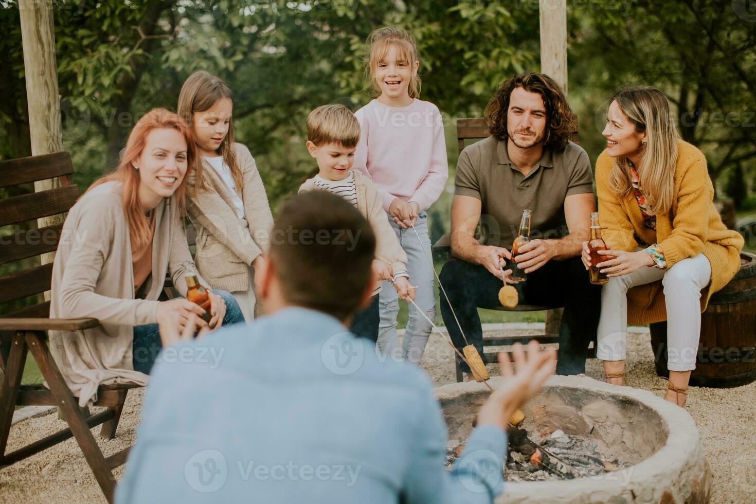 Friends having good time and baking corns in the house backyard photo