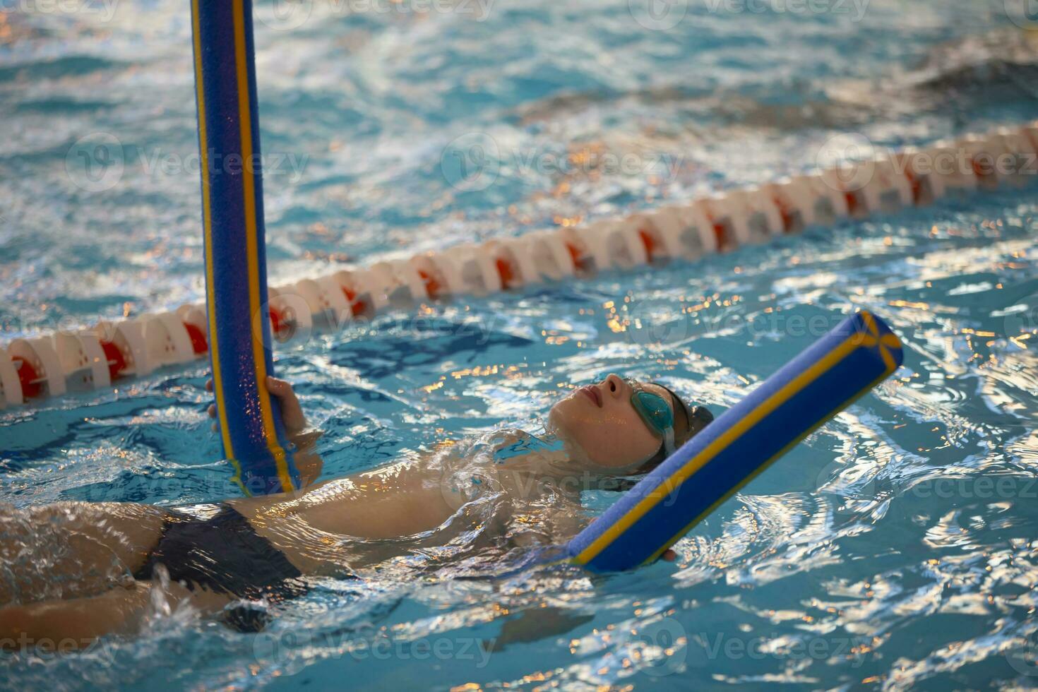 Boy in a swimming cap and swimming goggles in the pool. The child is engaged in the swimming section. photo