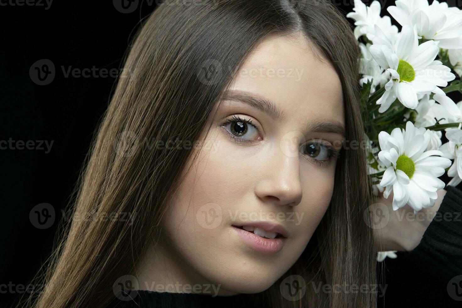 un hermosa joven niña con natural belleza con largo suave pelo sostiene un ramo de flores de blanco crisantemos foto