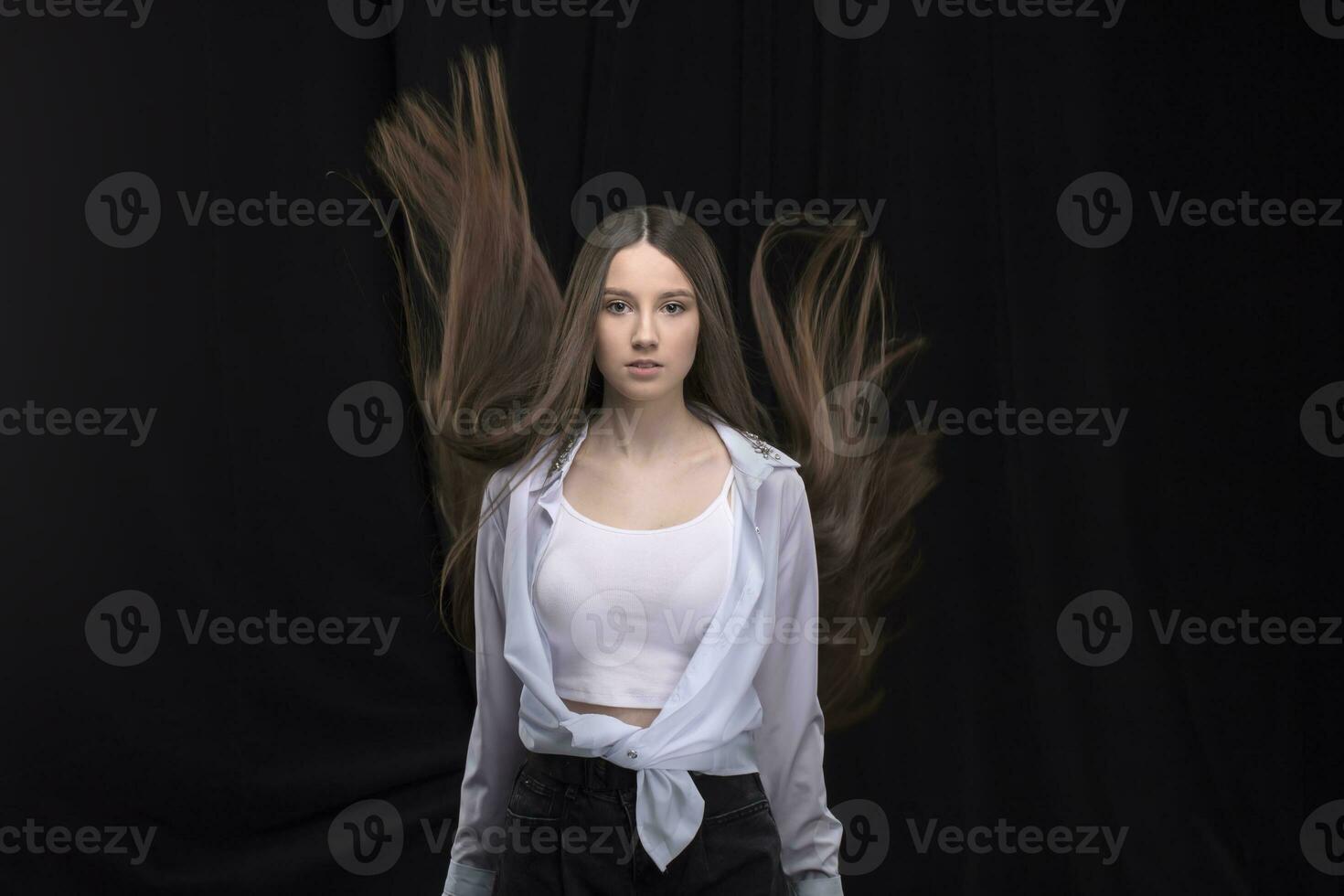 Beautiful brunette with long flying hair on a dark background. photo