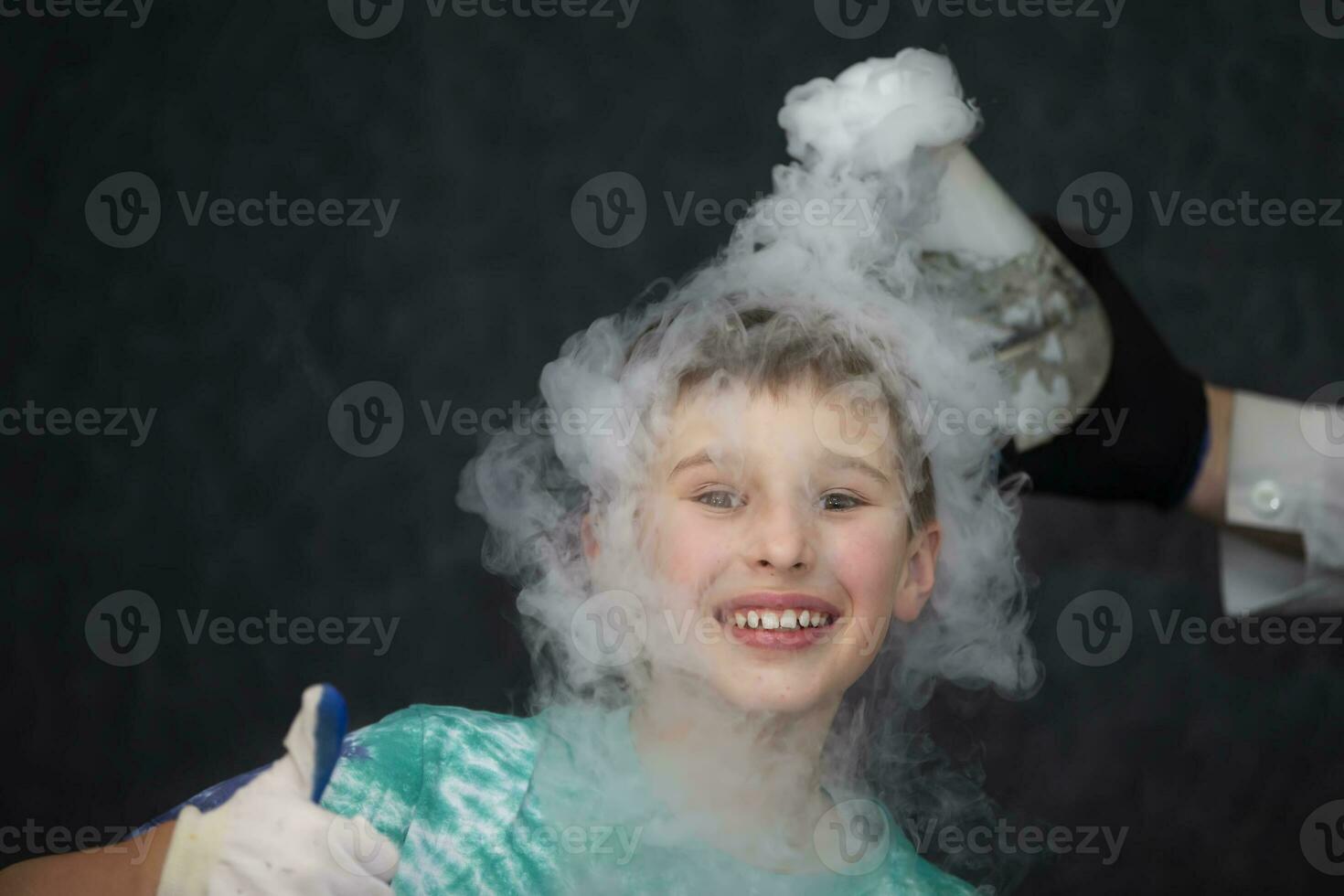 The child is a participant in scientific experiments. A boy in liquid nitrogen smoke. photo