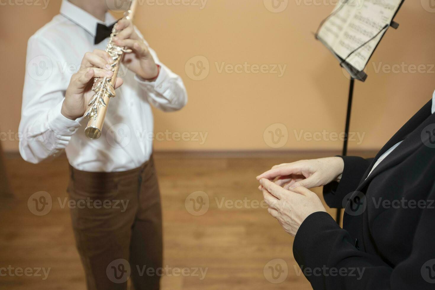 un música profesor escucha a un estudiante jugando el flauta en un música escuela. foto