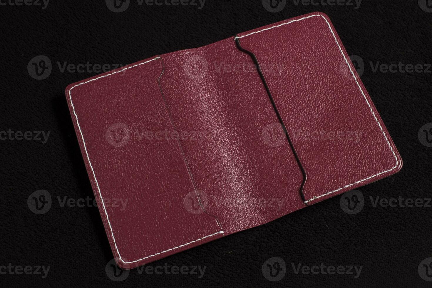 Open burgundy leather wallet with pockets on a dark background. photo
