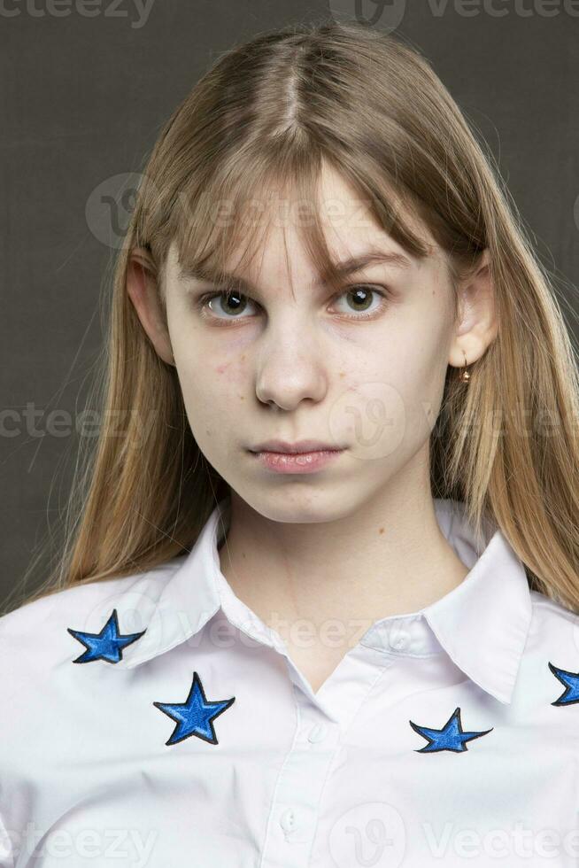 The face of a teenage girl with pimples close-up on a gray background. photo