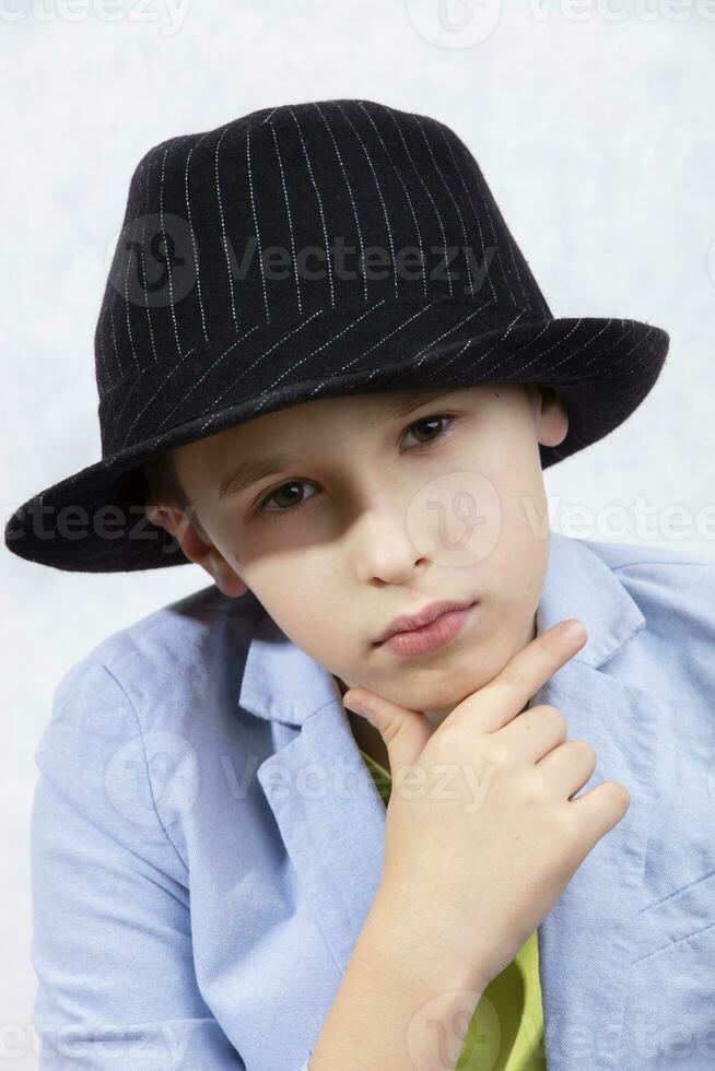 A handsome stylish boy in an elegant hat looks thoughtfully into the camera. Serious look. photo