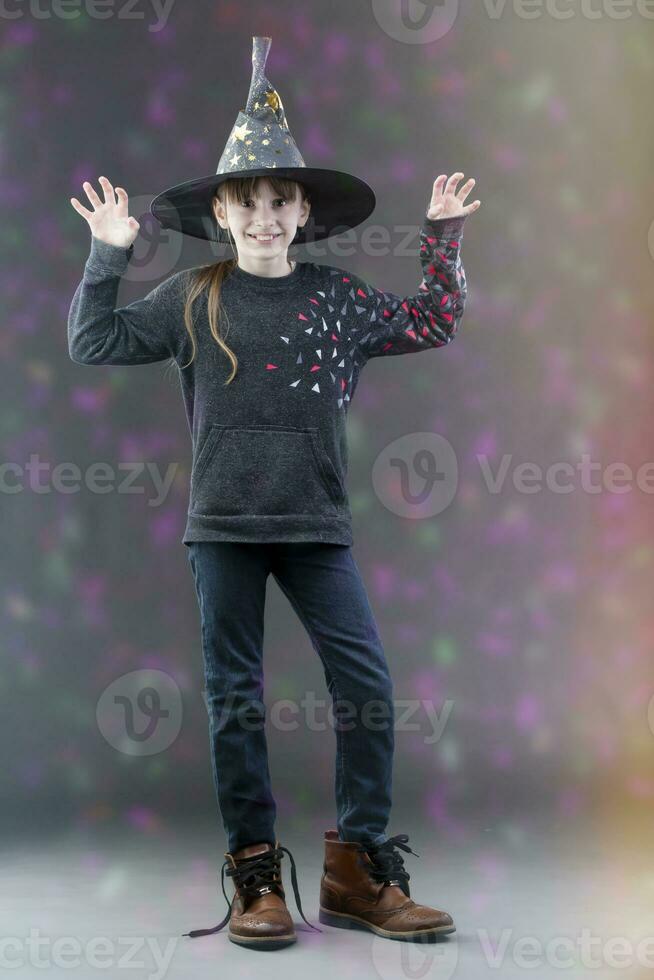 pequeño niña en un de bruja sombrero en un antecedentes con un multicolor lado. un niño a el fiesta de Hola. foto
