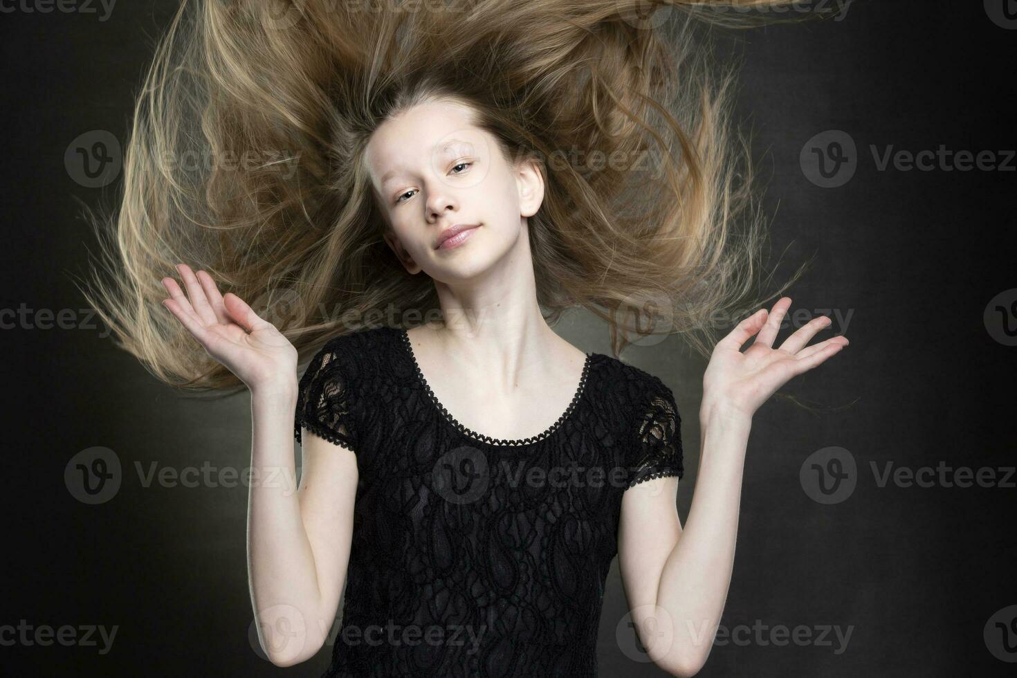 Beautiful teenager girl with flowing hair on a gray background. photo