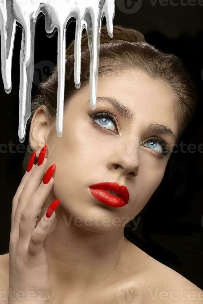 A white face cream flows against the background of a beautiful girl with red lips and nails. photo
