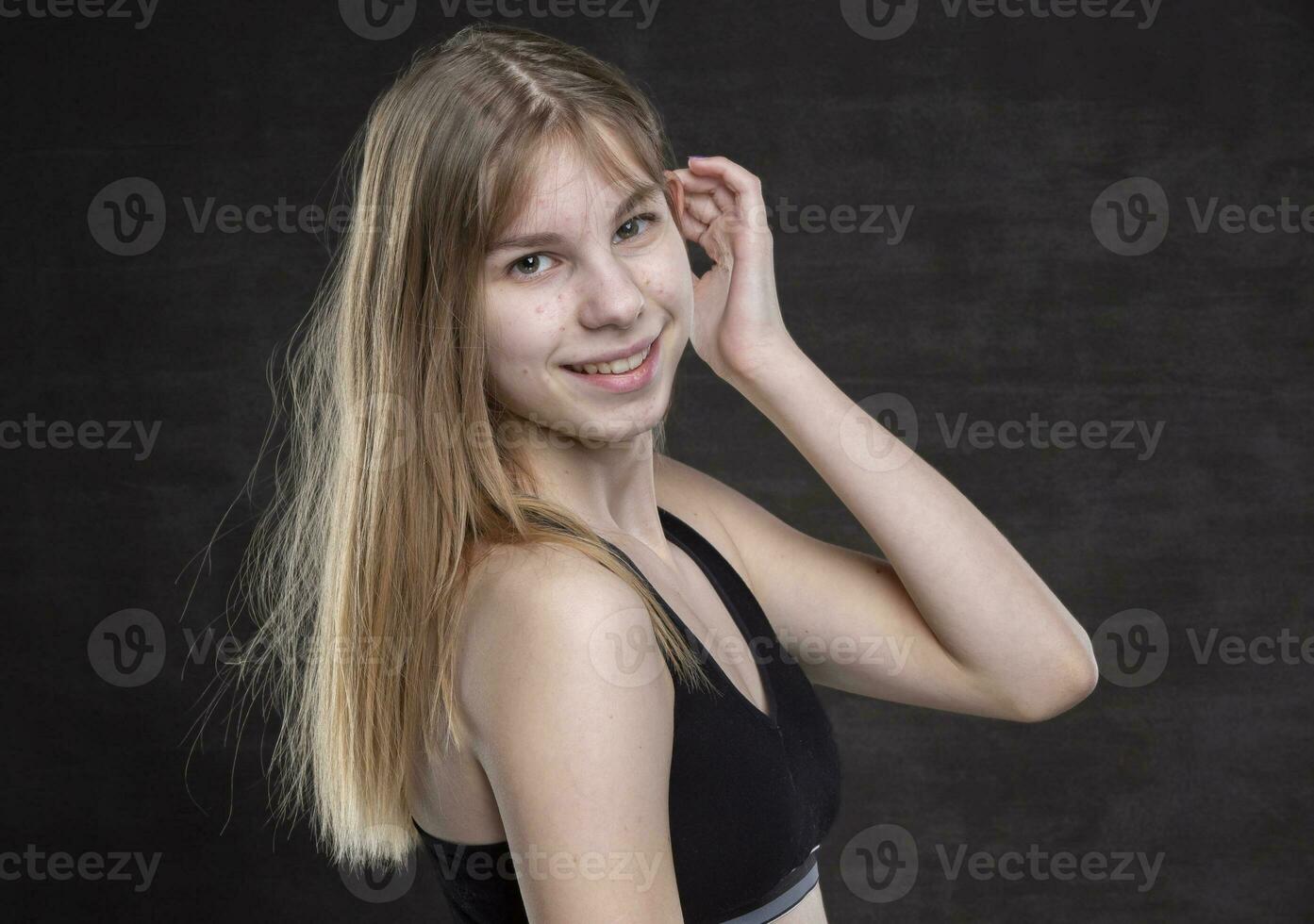 un Adolescente niña con espinillas en su cara en un Deportes camisa en un oscuro antecedentes. foto