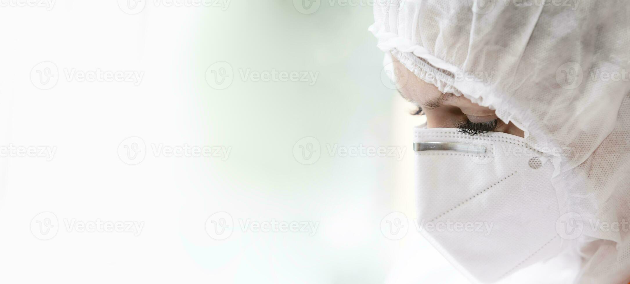 The face of a doctor in a protective medical mask and suit close-up on a white background. photo