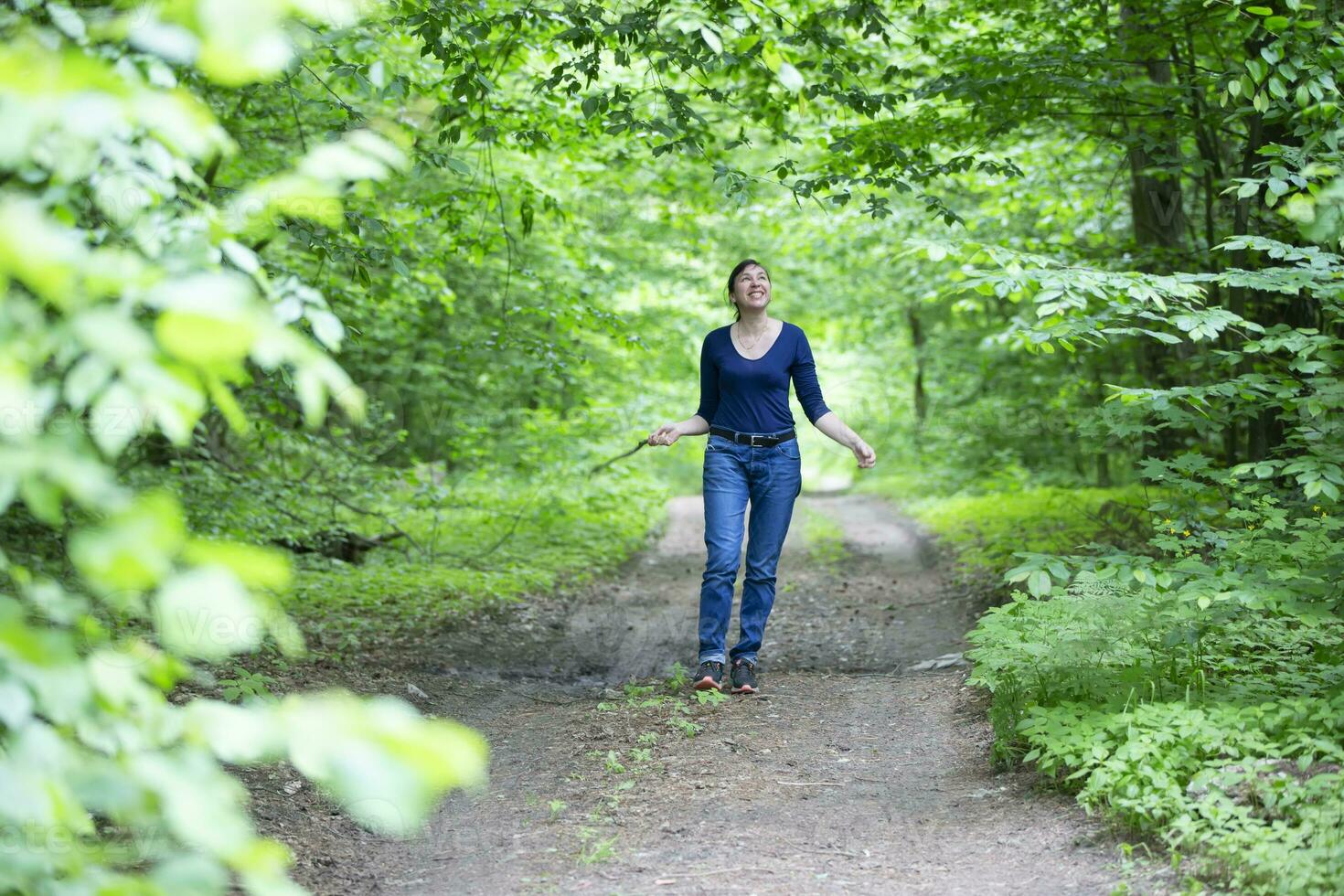 Happy middle-aged woman walks through the summer forest. photo