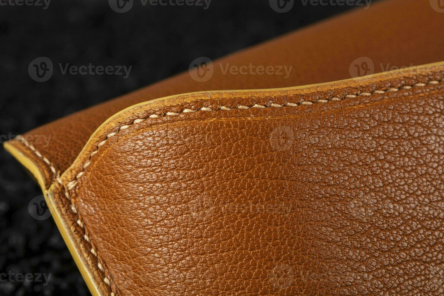 Part of a brown leather wallet or case with stitching. photo