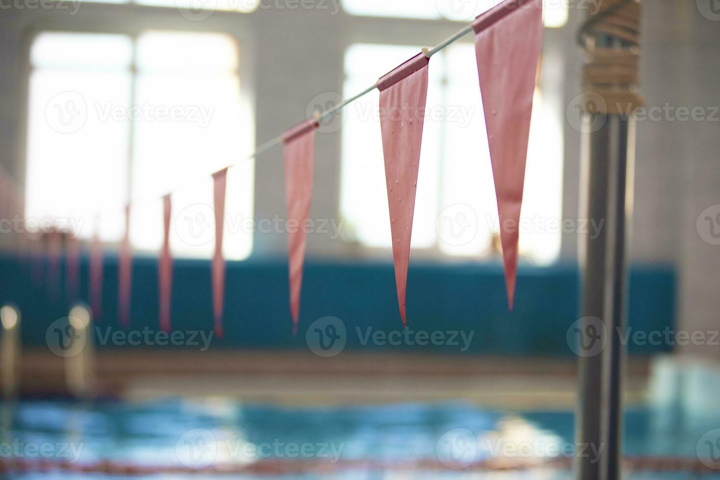 Red triangular flags against the blue water of the swimming pool. photo
