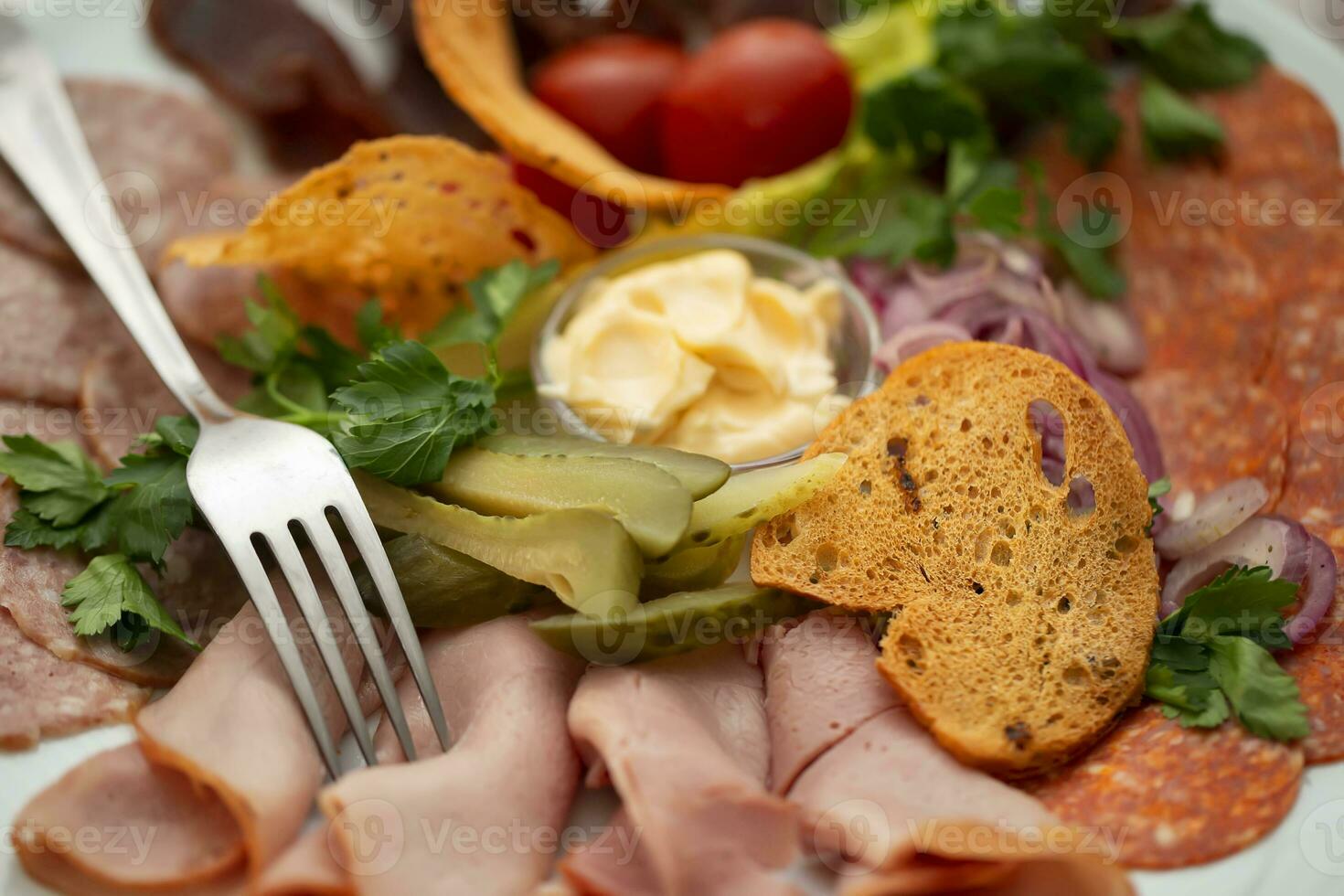On a plate, an appetizer of sliced meat with croutons and vegetables. photo
