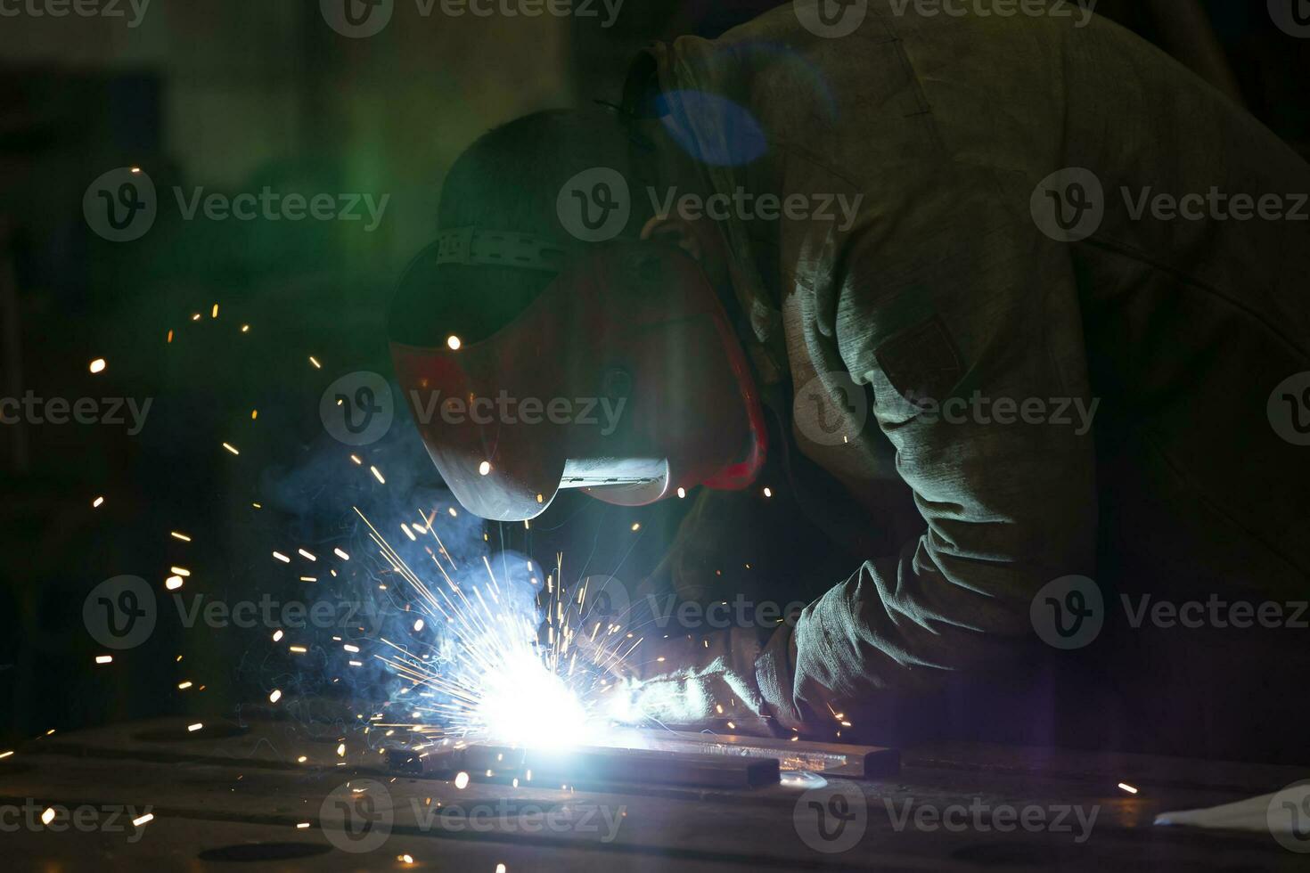 Welder at work. Man in a protective mask. The welder makes seams on the metal. Sparks and smoke when welding. photo