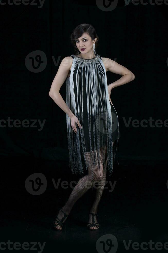 A beautiful girl dressed in the style of the 20-30s of the last century posing on a dark background. photo