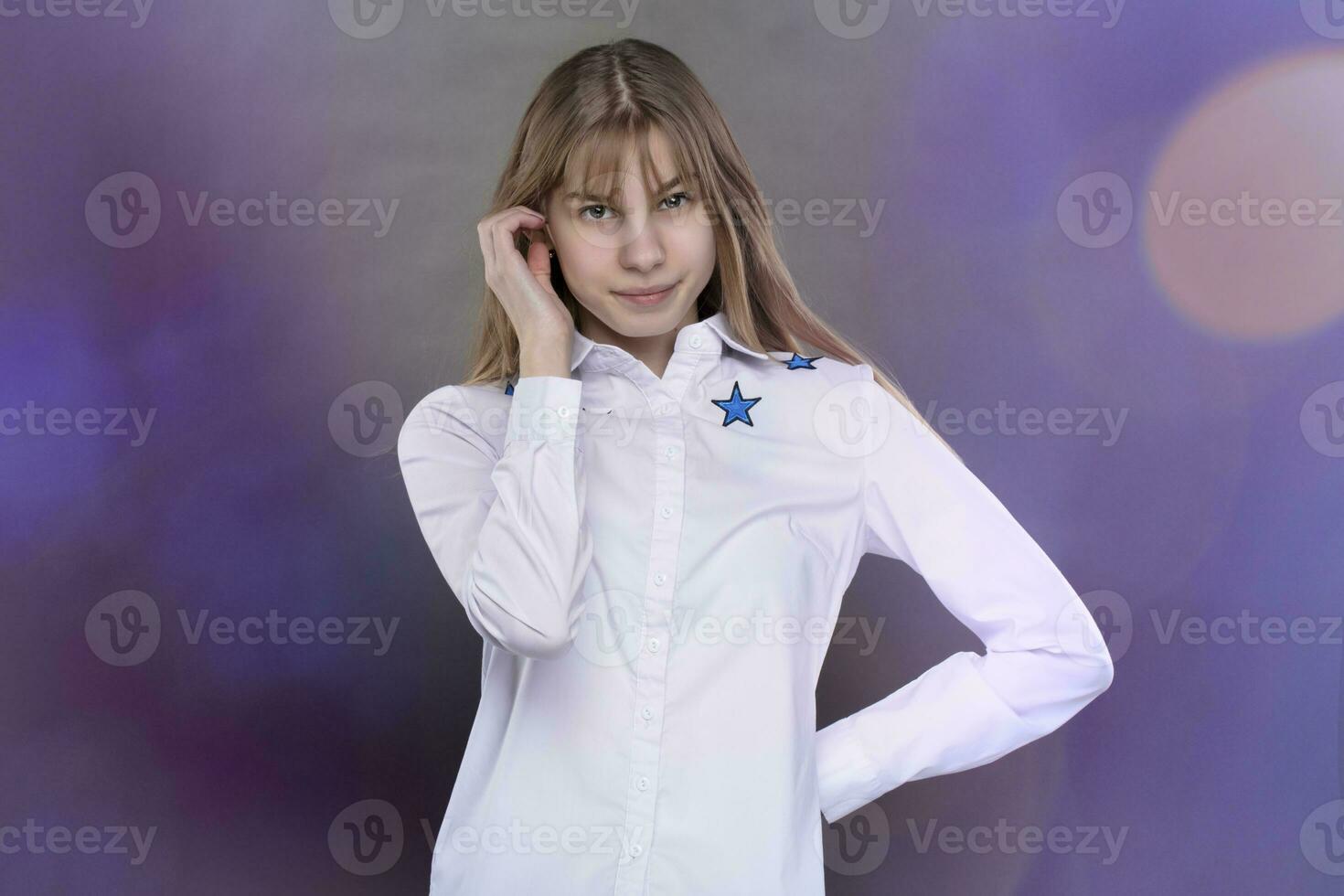 Happy teenage girl in a white shirt is shot against a gray background. photo