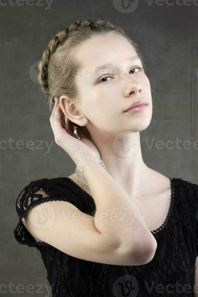 Beautiful teenager girl with a braid on a gray background. photo