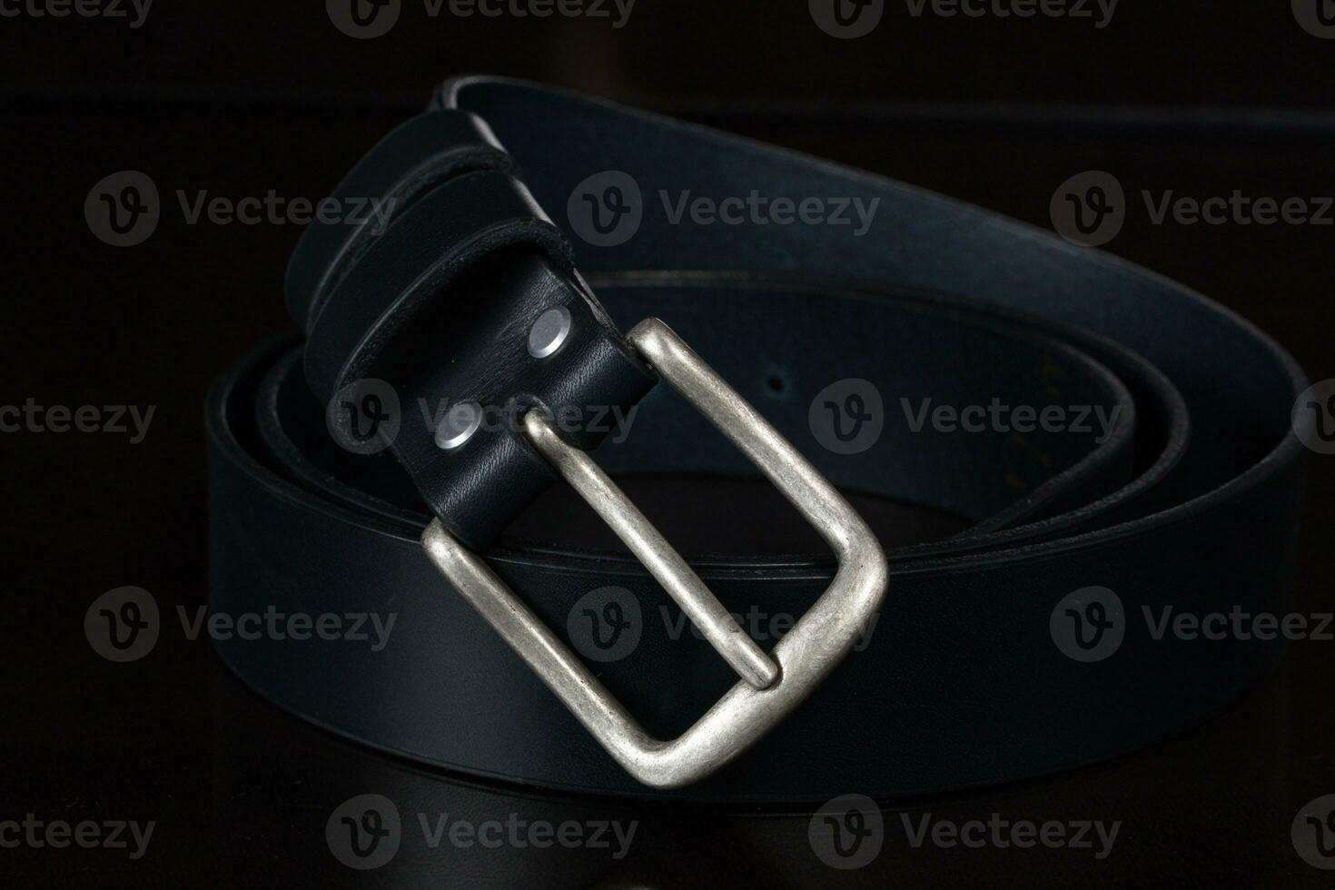 Leather belt with a metal buckle on a dark background close-up. photo