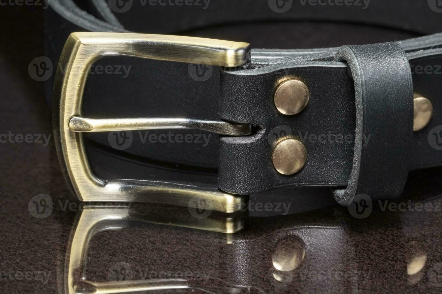 cuero cinturón con un dorado hebilla en un oscuro antecedentes de cerca. foto