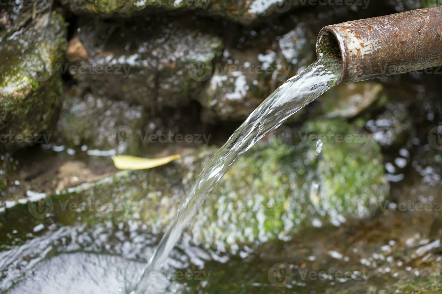 Spring water flows from a rusty pipe. photo