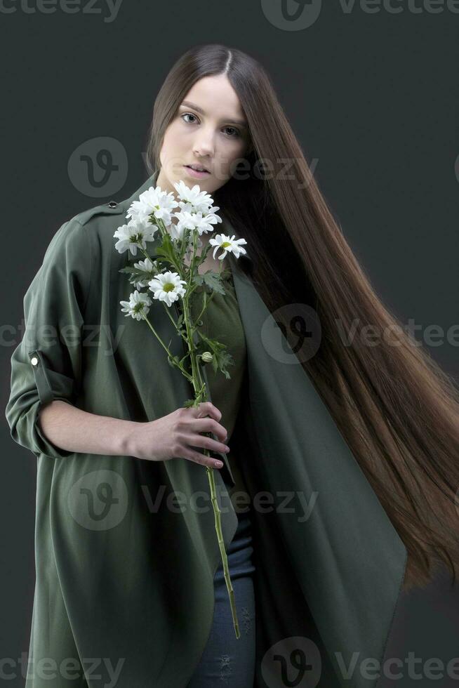 A beautiful young girl with natural beauty with long smooth hair holds a bouquet of white chrysanthemums. photo