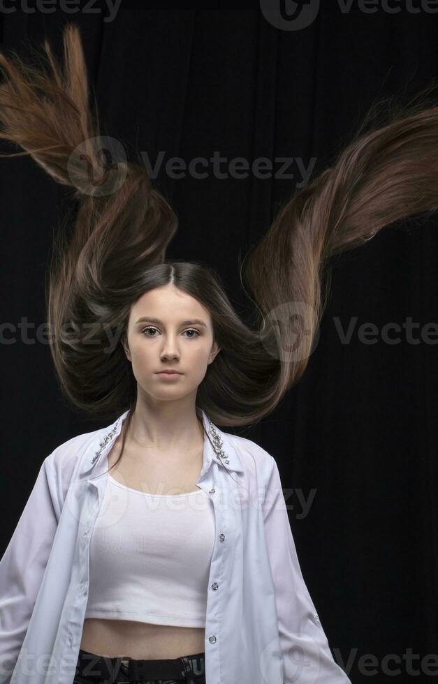 Beautiful brunette with long flying hair on a dark background. photo